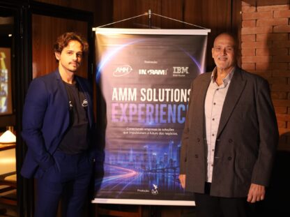 Bruno, da AMM Solutions, e um especialista convidado posam ao lado do banner do AMM Solutions Experience, evento realizado em parceria com IBM e Ingram Micro para discutir infraestrutura de TI, armazenamento de dados e Inteligência Artificial para o mercado audiovisual.